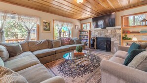 A cozy living room with a sectional sofa, a glass coffee table, a fireplace, and a bookshelf. - Walk to Beach and Town, Dogs OK, Cozy Fireplace, -Steelhead Mountain Retreat (Kings Beach)