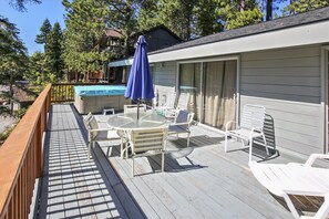 A deck with a hot tub, outdoor furniture, and a covered area with a blue umbrella. - Dollar Pointe of View- Hot Tub, Lake View, Close to Beach (Tahoe City)