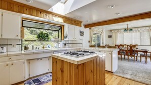 Eine Küche mit Holzausstattung, einer Kochinsel und einem Essbereich mit Tisch und Stühlen.