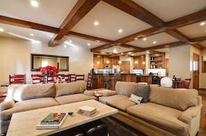 A spacious living room with a large sectional sofa, a coffee table, and a dining area with wooden chairs.