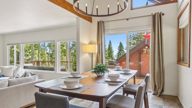 Un coin repas avec une table dressée pour quatre personnes, un canapé et un escalier menant à l’étage supérieur.