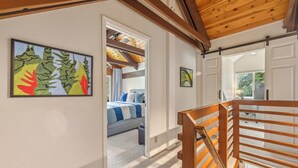 Une chambre à coucher avec un lit, un escalier en bois et un couloir menant à une autre pièce.