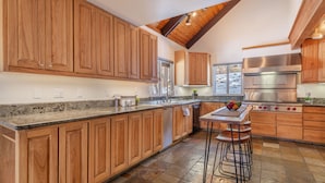 Une cuisine spacieuse avec des meubles en bois, un comptoir en granit, une cuisinière en acier inoxydable et un tabouret de bar.