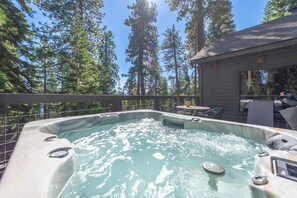 A hot tub surrounded by a wooden deck with a view of tall trees. - Lake View from Master Bedroom, Deck,  Hot Tub, HOA Beach Access -Scenic Solitude (Carnelian Bay)