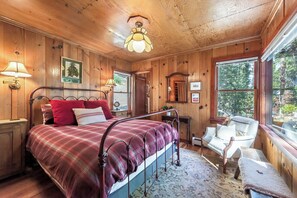 A wooden bedroom with a bed, a chair, a nightstand, and a window. - Lake View from Master Bedroom, Deck,  Hot Tub, HOA Beach Access -Scenic Solitude (Carnelian Bay)
