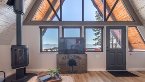 Une pièce chaleureuse avec un poêle à bois, de grandes fenêtres et une enseigne en bois sur laquelle on peut lire : « Pistaches de Californie ».