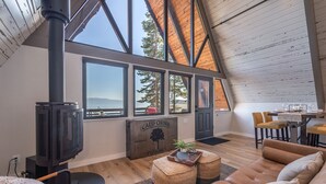 Un loft spacieux avec de hauts plafonds, de grandes fenêtres offrant une vue sur l’extérieur, une cheminée et un coin salon confortable.