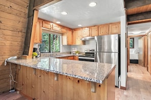 A modern kitchen with granite countertops, stainless steel appliances, and wooden cabinetry.