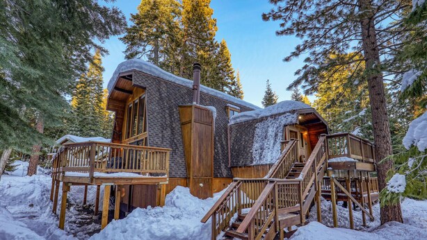 A cabin with a wooden deck and stairs, surrounded by snow and trees. - Short Drive to the Beach, Hot Tub, Large Deck - All Decked Out (Carnelian Bay)