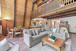 A spacious living area with a large sectional sofa, a dining table with chairs, and a kitchen in the background. - Short Drive to the Beach, Hot Tub, Large Deck - All Decked Out (Carnelian Bay)
