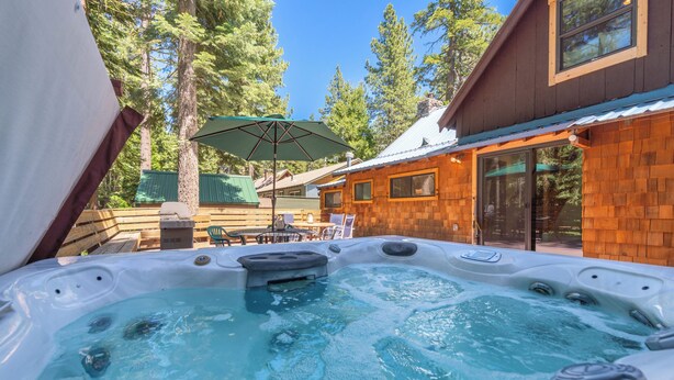 A hot tub with a wooden deck and a green umbrella, surrounded by trees and a wooden building. - Walk to Tahoe Park Private Beach, Hot Tub, Dogs OK- Cedar Crest (Tahoe City)