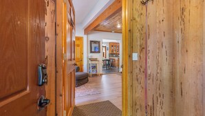 A wooden interior hallway leading to a kitchen area with a rug, a bench, and a door with a handle. - Walk to Tahoe Park Private Beach, Hot Tub, Dogs OK- Cedar Crest (Tahoe City)