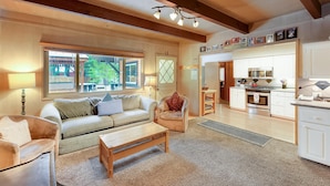 A cozy living room with a sofa, a wooden coffee table, and a dining area with a kitchen in the background.