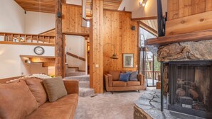 A cozy living room with a stone fireplace, a wooden staircase, and a leather sofa. - Alpine Getaway - N. Lake Tahoe, Hot Tub, Mountain Views (Alpine Meadows)