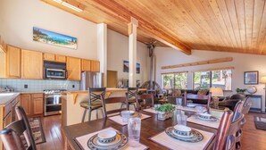 A spacious kitchen with wooden cabinets, a dining area with a large table set for four, and a cozy living room with a fireplace. - Overlook Cabin, Good View, Walk to Tahoe City, Wood Stove (Tahoe City)