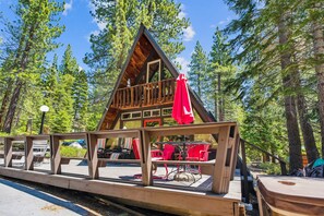 A cabin with a balcony, red chairs, and a table. - Adventures of the A-frame- 3BR w/ Hot Tub, Backs to forest- Dogs OK! (Carnelian Bay)