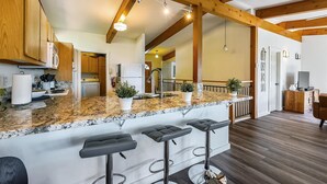 Una cocina con encimeras de granito, vigas de madera y una zona de bar con taburetes.