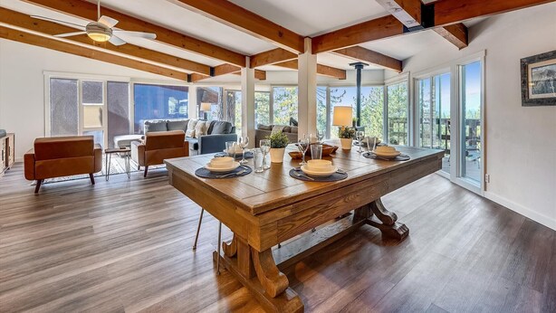 Un comedor amplio con una gran mesa de madera, sillas modernas y un ventilador de techo.