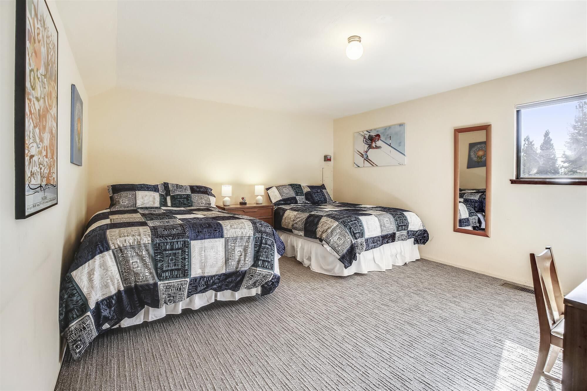 Un dormitorio con dos camas, una ventana y un espejo.