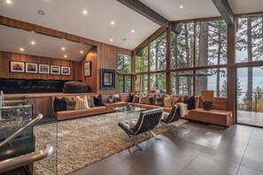 Un amplio salón con un ventanal grande, una chimenea y un conjunto de asientos.