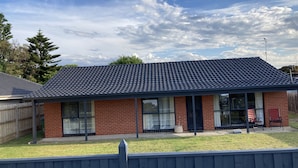 A two-story house with a tiled roof, brick exterior, and large windows.