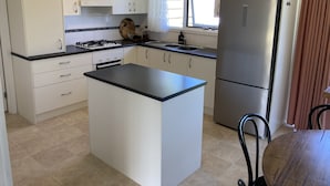 A modern kitchen with white cabinets, a central island, a stove, and a refrigerator.