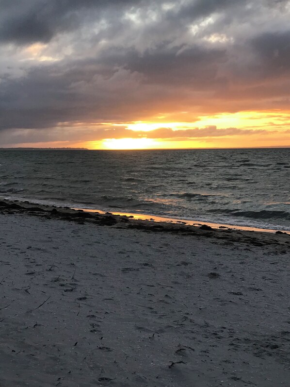 Ein Strand mit Blick auf den Ozean und einen Sonnenuntergang.