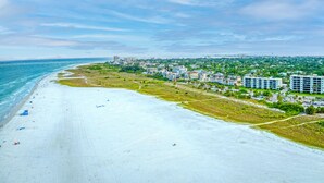 A beach with a row of beachfront condos, a sandy beach, and a clear view of the ocean. - Siesta Breeze Retreat | Luxury Condo on SK w/ Heated Pool, Walking Distance to Beach & Village! (Siesta Key)