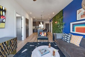 A modern living room with a sofa, coffee table, and a view into the kitchen.