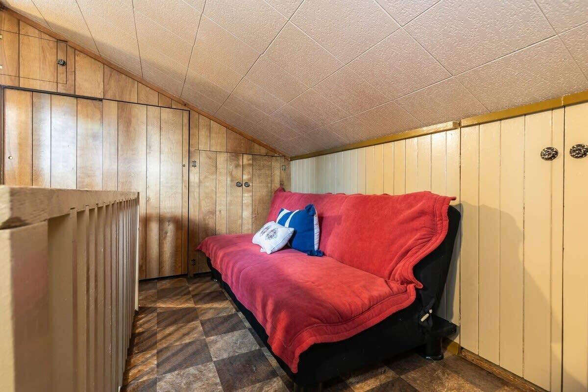 A room with a red sofa, wooden panel walls, and a checkered floor.