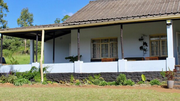 A two-story house with a tiled roof, a covered porch, and a stone foundation. - Lovely 4 bed in Mutare - 2178 (Mutare)