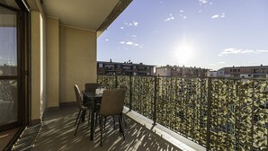 Un balcon avec une table et des chaises, une clôture décorée et une vue sur des bâtiments en arrière-plan.