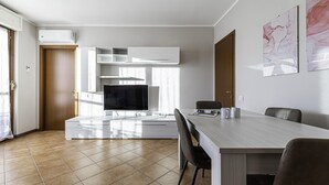 Une cuisine moderne dotée d’un four encastré, d’un téléviseur à écran plat et d’un coin repas avec une table et des chaises.