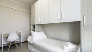 A modern, minimalist bedroom with a single bed, a desk, and built-in wardrobe. - Piazza Alboreto 72 - Rozzano (Rozzano)