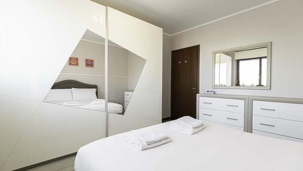Une chambre à coucher moderne avec un lit, une commode, un miroir et une armoire.