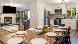Une cuisine moderne avec des meubles blancs, un pare-feu noir et blanc et des appareils électroménagers en acier inoxydable.
