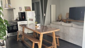 Una cocina moderna con una mesa y un banco de madera, horno empotrado y refrigerador.
