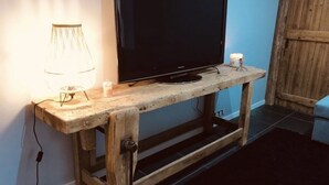 Un mueble bajo de madera con un televisor de pantalla plana, una lámpara y una vela.