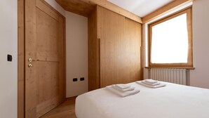 Una camera da letto con un armadio in legno, una finestra vista e un letto ben rifatto.
