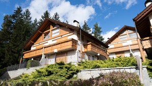 Un edificio in stile chalet con tetto spiovente, balconi in legno e un muro di sostegno in pietra.