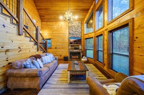 Ein rustikales Holzhaus-Interieur mit Kamin, Holzwänden, einer Couch und einer Treppe.