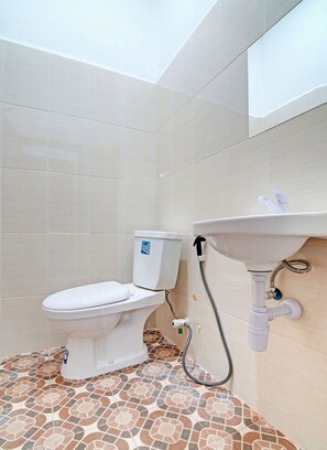 Une salle de bain avec des toilettes, un lavabo et un sol carrelé.