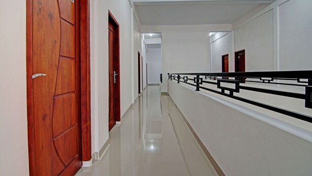 A hallway with wooden doors, a black railing, and a tiled floor. - Hotel O Penginapan Sarinah SyariahNearRM Beringin Indah (Pangkalan Kuras)