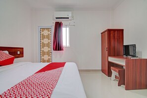 Une chambre d’hôtel équipée d’un lit, d’un bureau, d’une télévision et d’un climatiseur.