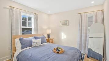 A bedroom with a bed, bedside table, lamp, and a mirror.