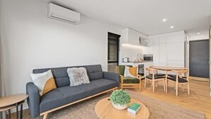 A modern living room with a sofa, a coffee table, and a dining area with chairs.