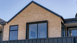 A modern building with a triangular roof, large windows, and a dark exterior wall. - Mountain View Apartment Steps from the Village (Wanaka)