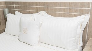 A bed with white bedding and pillows, a wooden headboard, and a bedside table with a telephone. - Hotel Cinco Monteria (Montería)