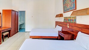 Een hotelkamer met twee bedden, een houten kledingkast, een bureau en een klein bankje.