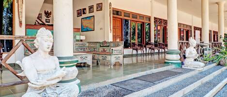 A serene courtyard with stone statues, a wooden bench, and a map on the wall.